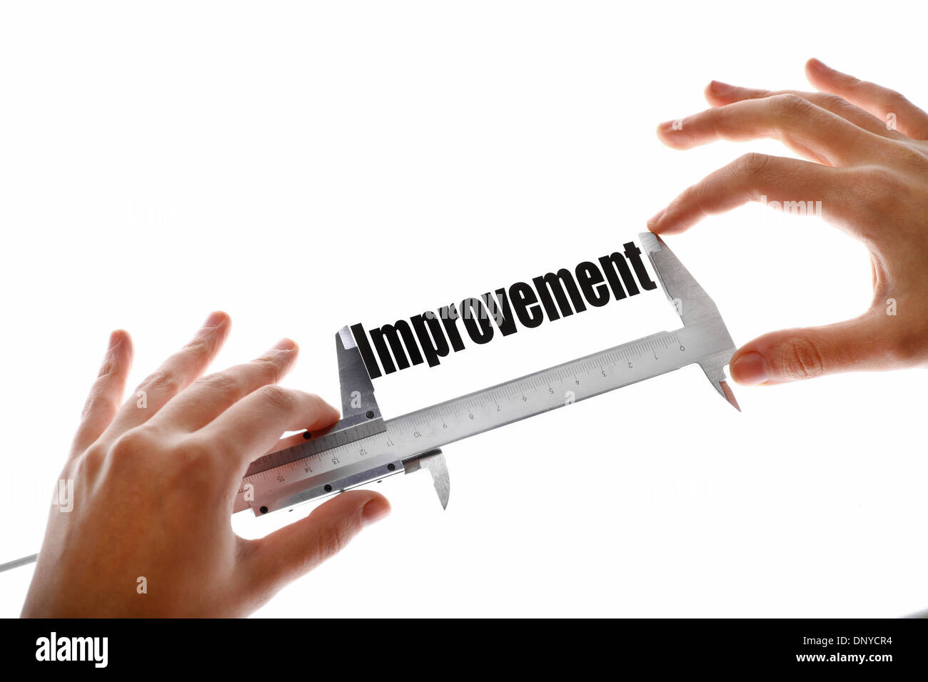 Due mani tenendo un calibro, misurare la parola "miglioramento". Foto Stock
