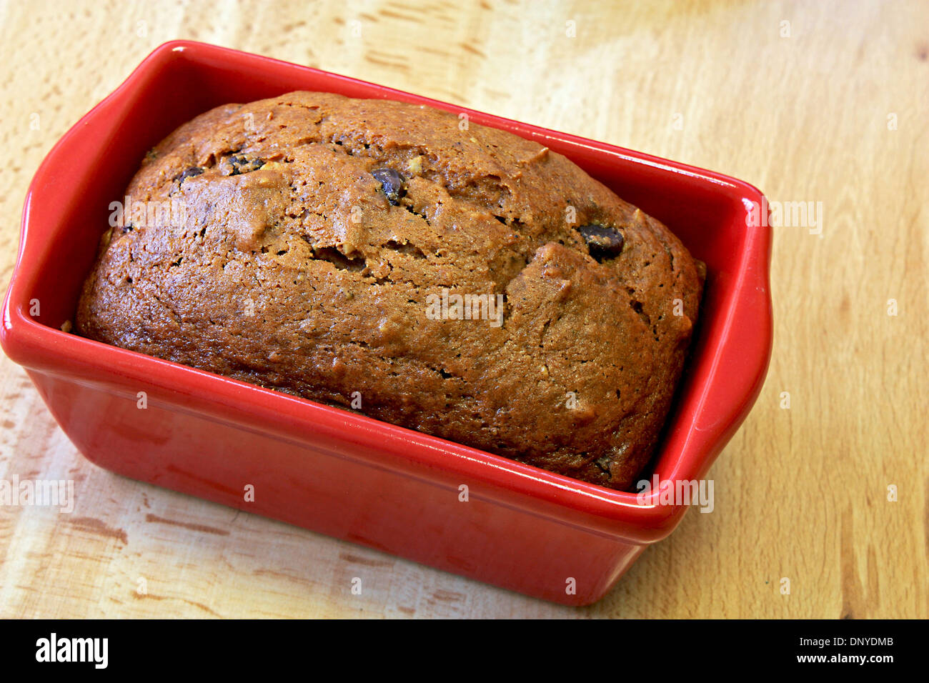 La zucca chocolate chip il pane in un rosso teglia per il pane su un tavolo da cucina fresco di forno Foto Stock
