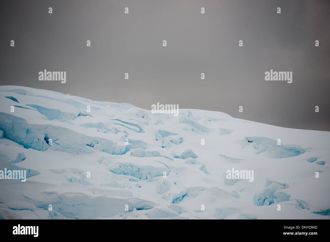 Antartide - profondi crepacci di un ghiacciaio lungo il canale di Lemaire sulla penisola Antartica si stagliano contro il grigio cielo nuvoloso. Foto Stock