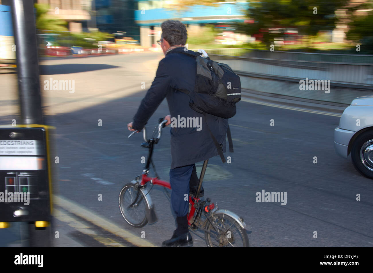 Uomo su una bicicletta pieghevole in London negoziando una rotatoria. Foto Stock