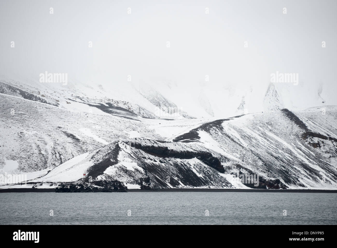 Antartide - La neve copre la scura roccia vulcanica di Whalers Bay sull isola Deception. Isola Deception, a sud le isole Shetland, è una caldera di un vulcano ed è composta di roccia vulcanica. Foto Stock