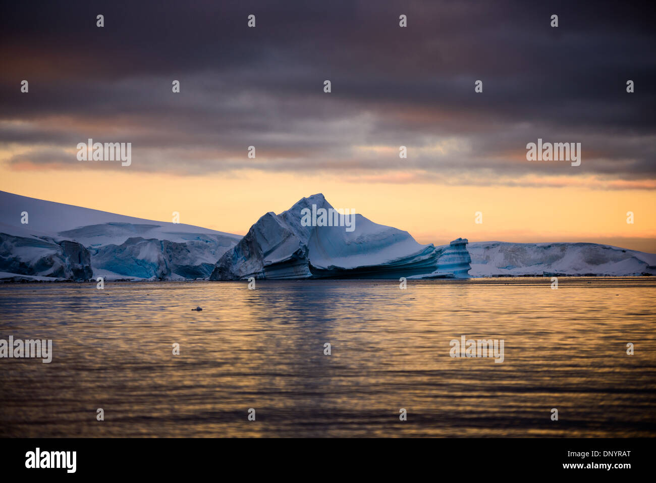 Antartide - un iceberg si staglia contro i colori del sole che tramonta in Hughes Bay in Antartide. Foto Stock