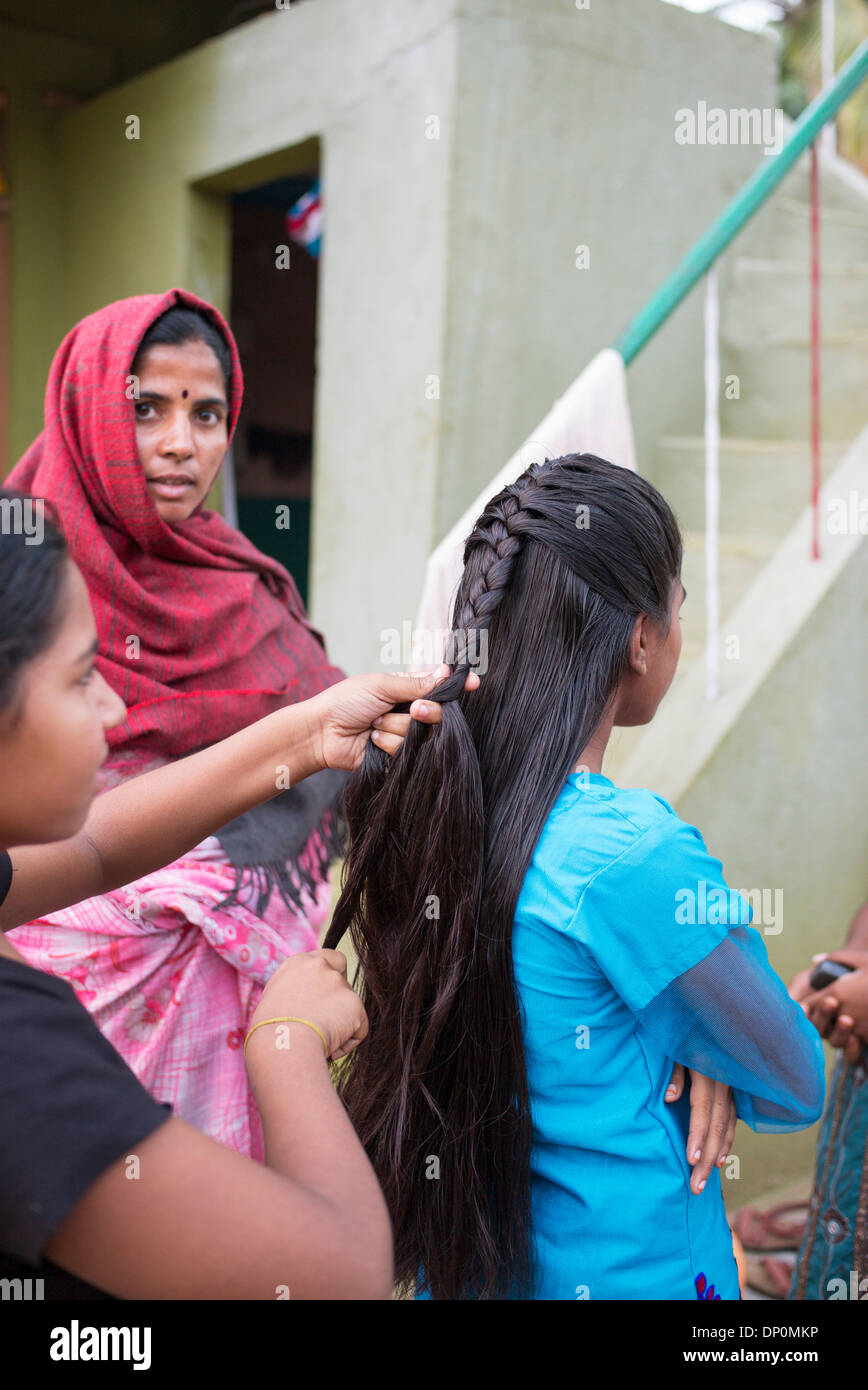 Rurale villaggio indiano ragazza adolescente avente i suoi capelli intrecciati. Andhra Pradesh, India Foto Stock