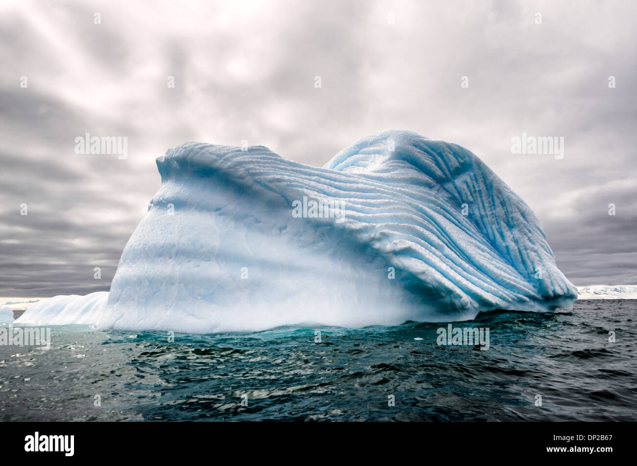 Antartide - un iceverg galleggianti nelle acque antartiche, con inciso profondamente scanalature formanti pattterns nel lato creato da intrappolata aria compressa la fuga come un iceberg si scioglie lentamente. Foto Stock