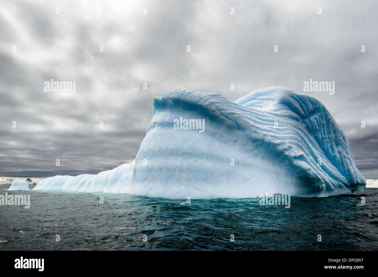 Antartide - un iceverg galleggianti nelle acque antartiche, con inciso profondamente scanalature formanti pattterns nel lato creato da intrappolata aria compressa la fuga come un iceberg si scioglie lentamente. Foto Stock