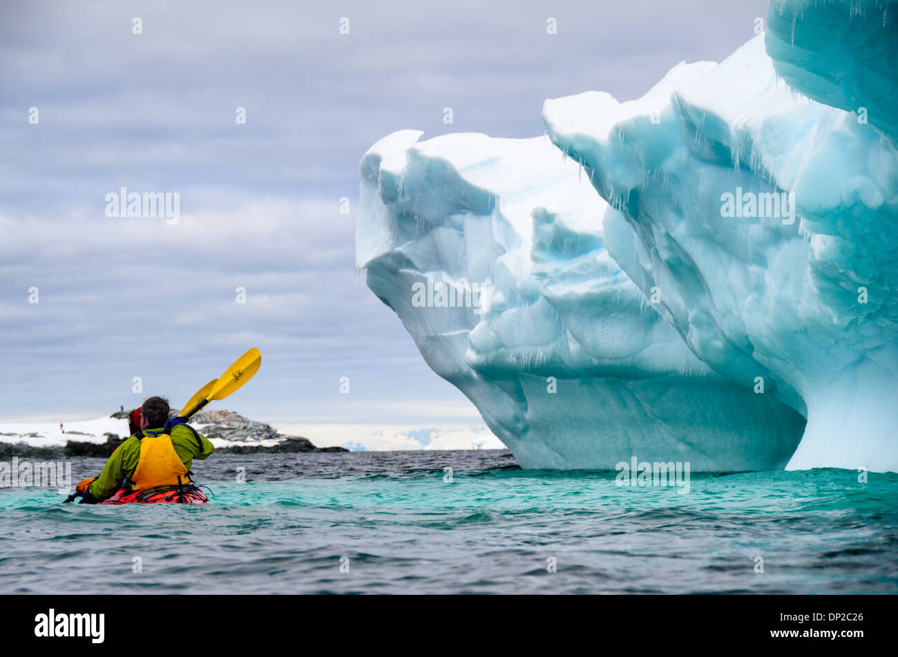 Antartide - Kayakers in un tandem Kayak scivolano passato un iceberg che è stato si inclina lentamente a rocce Hydrurga a due Hummock isola. La regione è nota come un preferito per leopard guarnizioni (Hydrurga leptonyx). Foto Stock