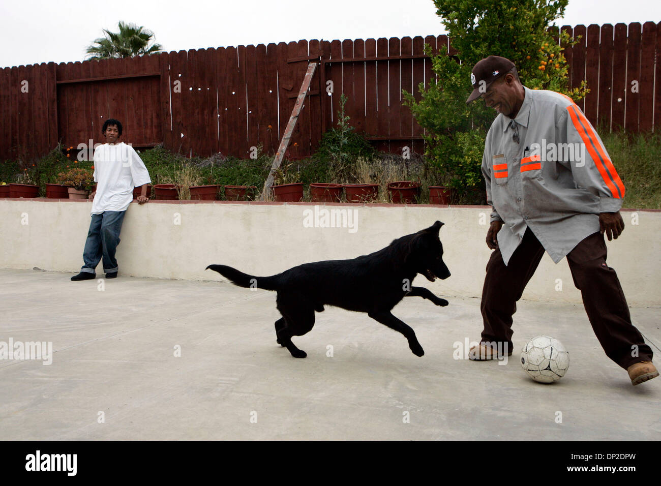 Maggio 29, 2006; San Diego, CA, Stati Uniti d'America; Travis Lowe, sinistra, 17 anni, orologi come suo padre Ronald Lowe, Suor gioca con il cane di famiglia, 'Cesar' quali sono prelevati come un cucciolo in Van Horn, Texas, quando stavano fuggendo Katrina per la sicurezza di una casa temporanea a San Diego dove parenti offerto rifugio. Il Lowes hanno deciso di rimanere a San Diego e si adegua alla vita qui. Travis ho Foto Stock