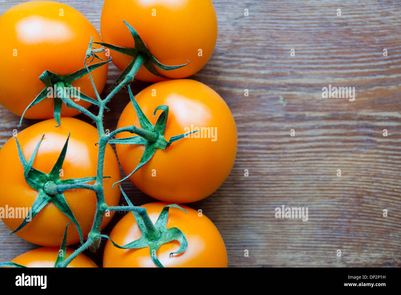 Succosa freschi pomodori arancione su vintage tavolo in legno Foto Stock