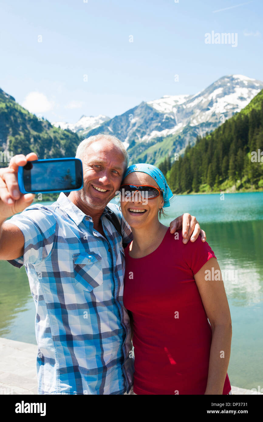 Uomo maturo e la donna di scattare una foto di loro stessi, il lago Vilsalpsee, Valle di Tannheim, Austria Foto Stock