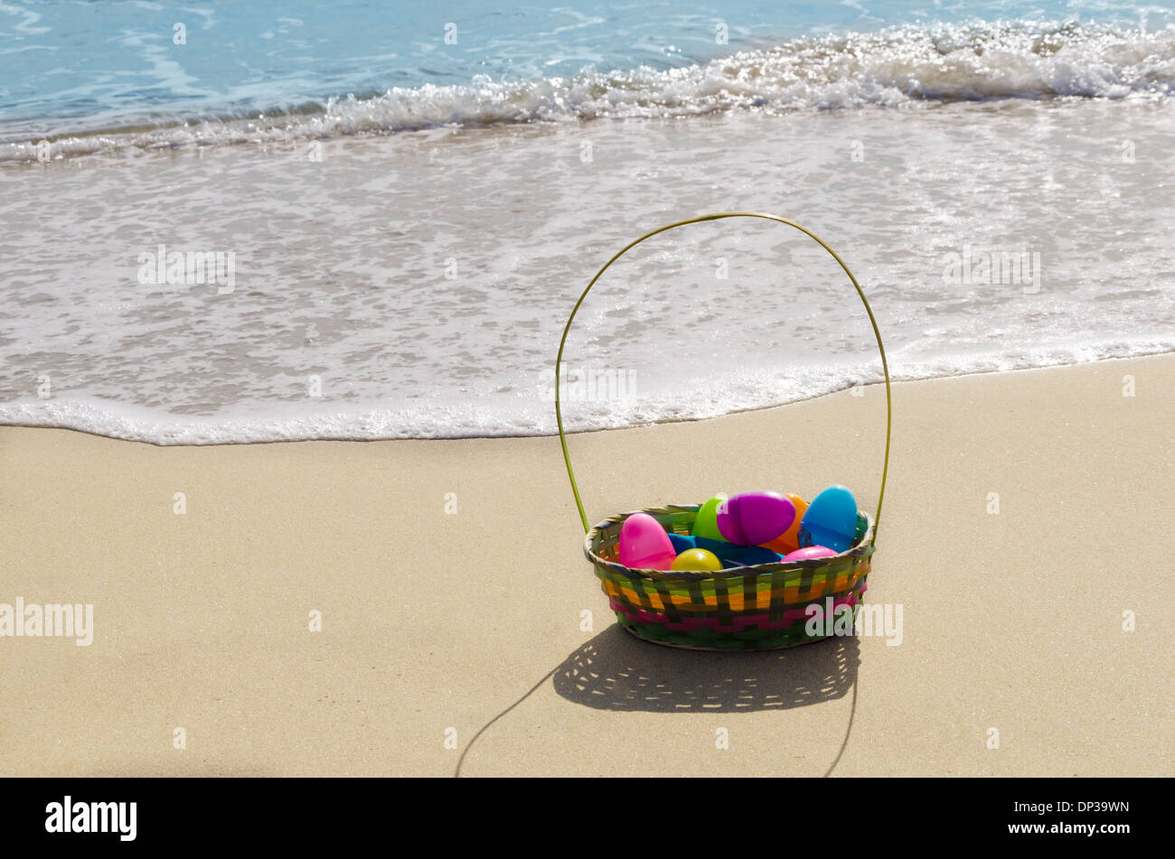 Cesto di pasqua con le uova sulla spiaggia di sabbia in riva all'oceano Foto Stock