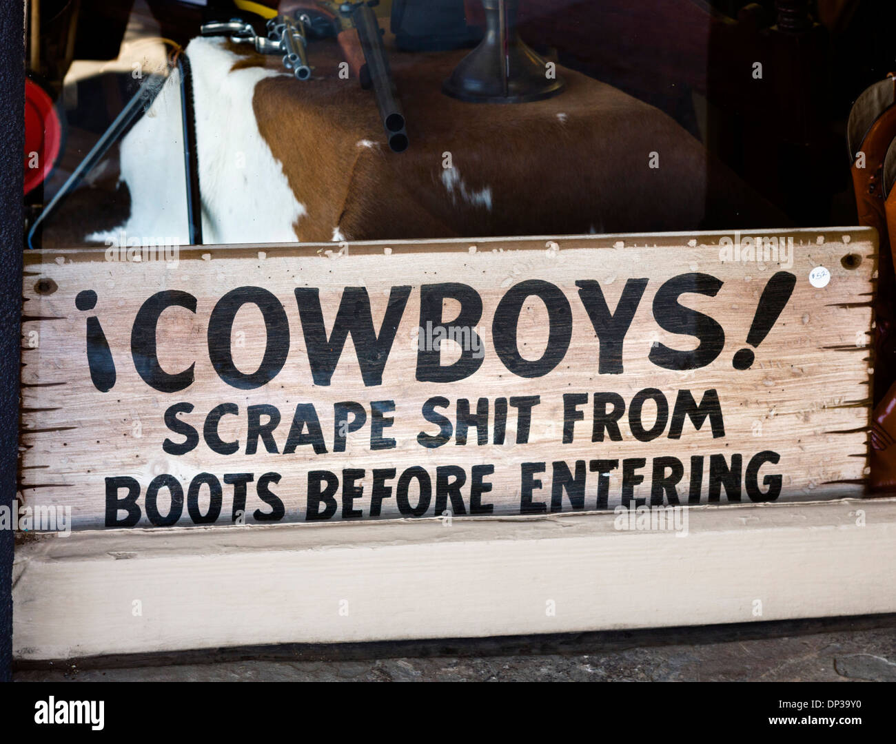 I cowboys raschiare merda da stivali prima di entrare nel segno di una vetrina sulla strada principale nel centro cittadino Moab, Utah, Stati Uniti d'America Foto Stock