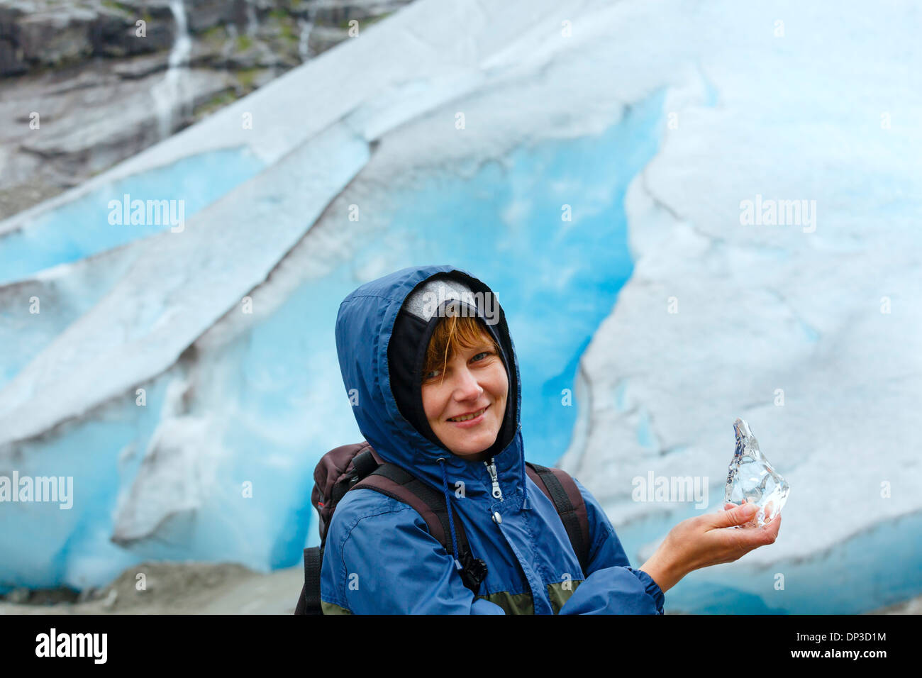 Ritratto di donna felice con un pezzo di ghiaccio in mano sul ghiacciaio Nigardsbreen sfondo (Norvegia) Foto Stock