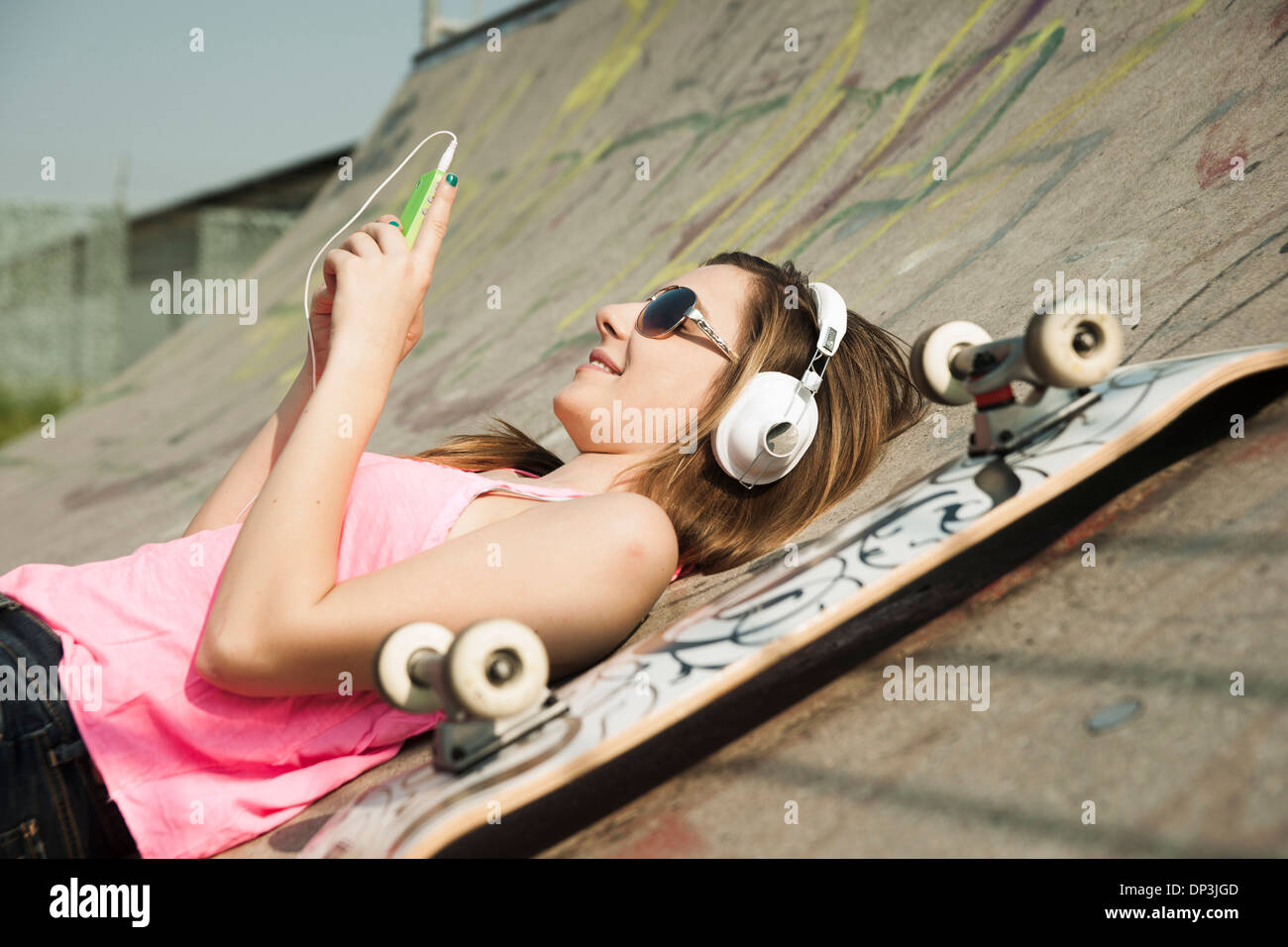 Ragazza adolescente ascoltando MP3 Player in Skatepark, Feudenheim, Mannheim, Baden-Württemberg, Germania Foto Stock