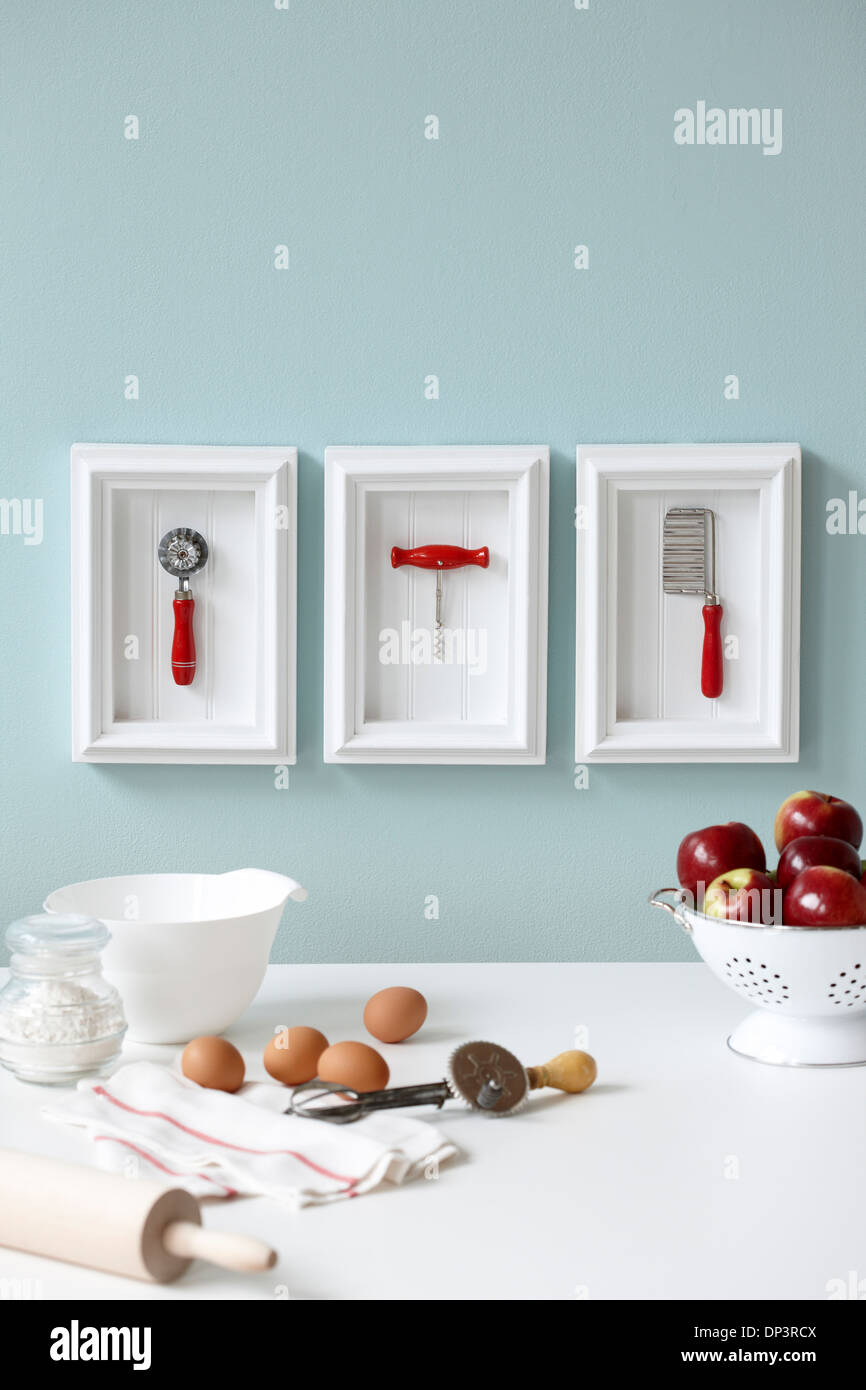 Utensili incorniciata sulla tabella di cucina con le mele, le uova e il recipiente di miscelazione Foto Stock