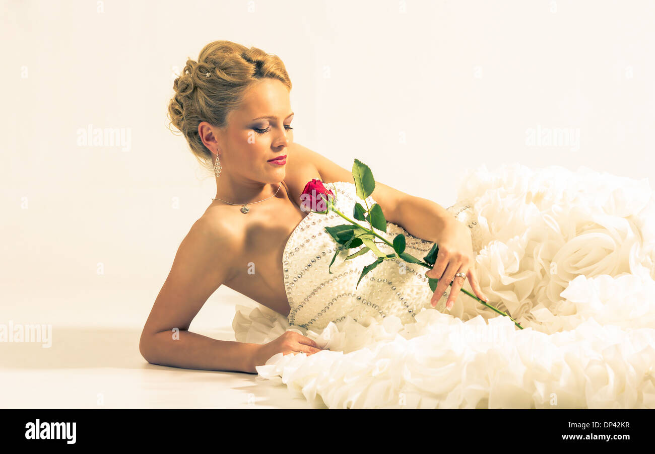 Bella Sposa che stabilisce, tenendo una rosa in mano Foto Stock