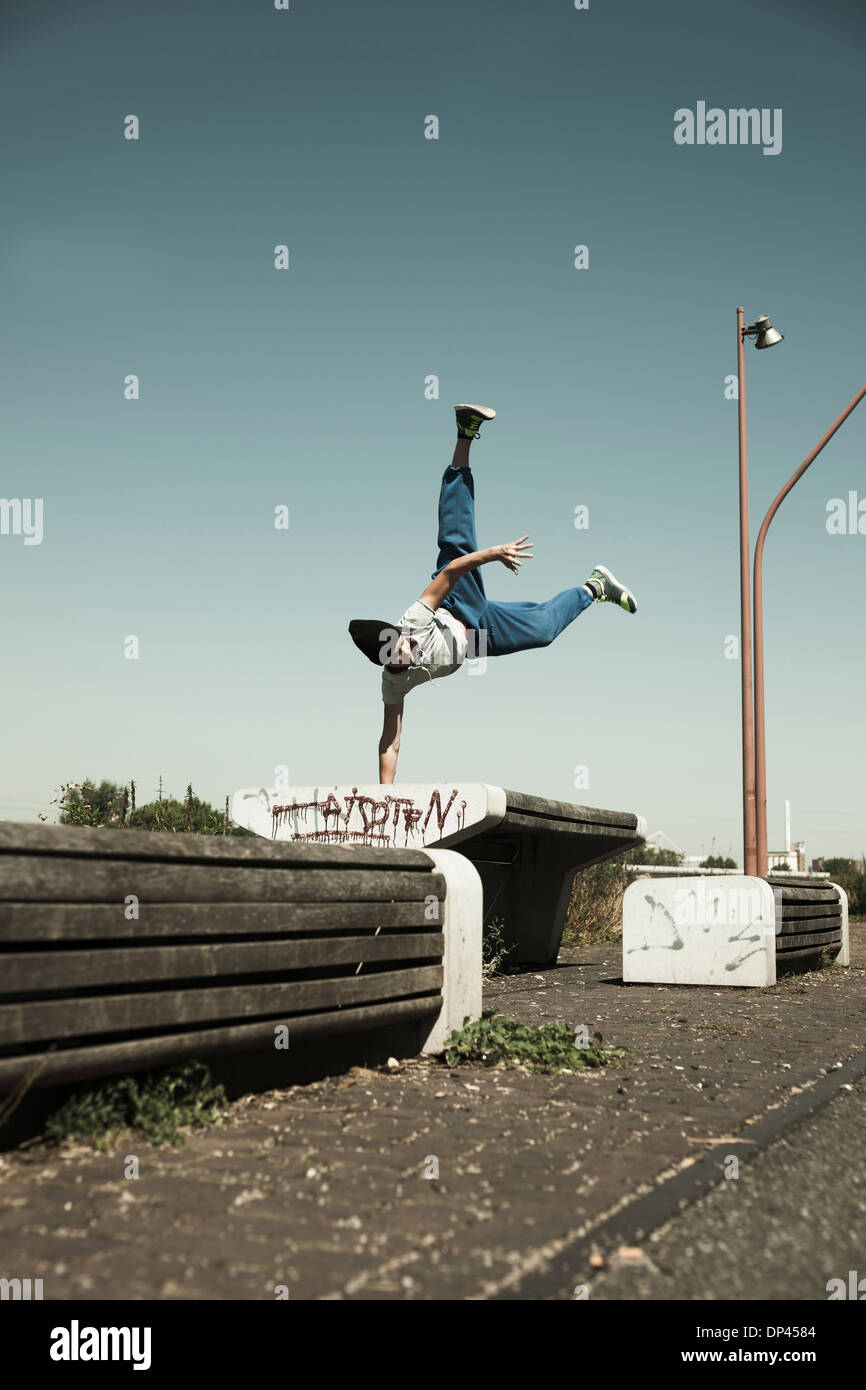 Ragazzo adolescente facendo handstand sulla barriera, freerunning, Germania Foto Stock