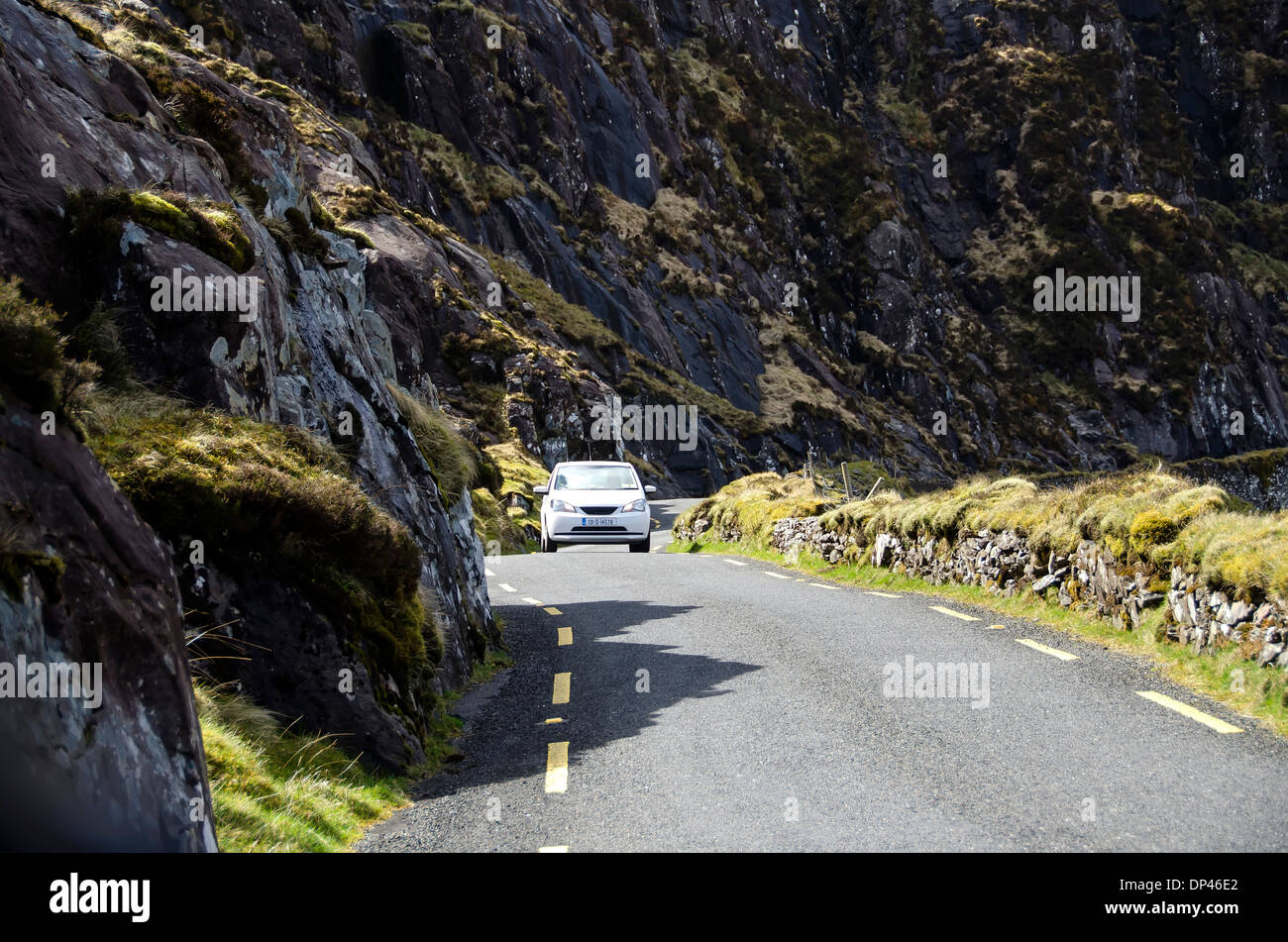 Auto sulle strette a due vie in discesa su strada il Conor Pass da Dingle town a Dunmore Testa, penisola di Dingle, nella contea di Kerry, Irlanda Foto Stock