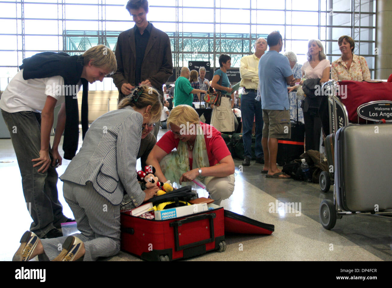 Agosto 10, 2006; Los Angeles, CA, Stati Uniti d'America; una famiglia francese passaggi loro valigia combinando il loro bagaglio a mano con il bagaglio in stiva come sono in attesa in linea presso il Tom Bradley International terminal a LAX per essere emesso per il loro viaggio a Londra su British Airways dopo un complotto terrorista è stato sventato a Londra Giovedì, 10 agosto 2006. Gli aeroporti sono su livelli elevati di protezione a causa della National Foto Stock
