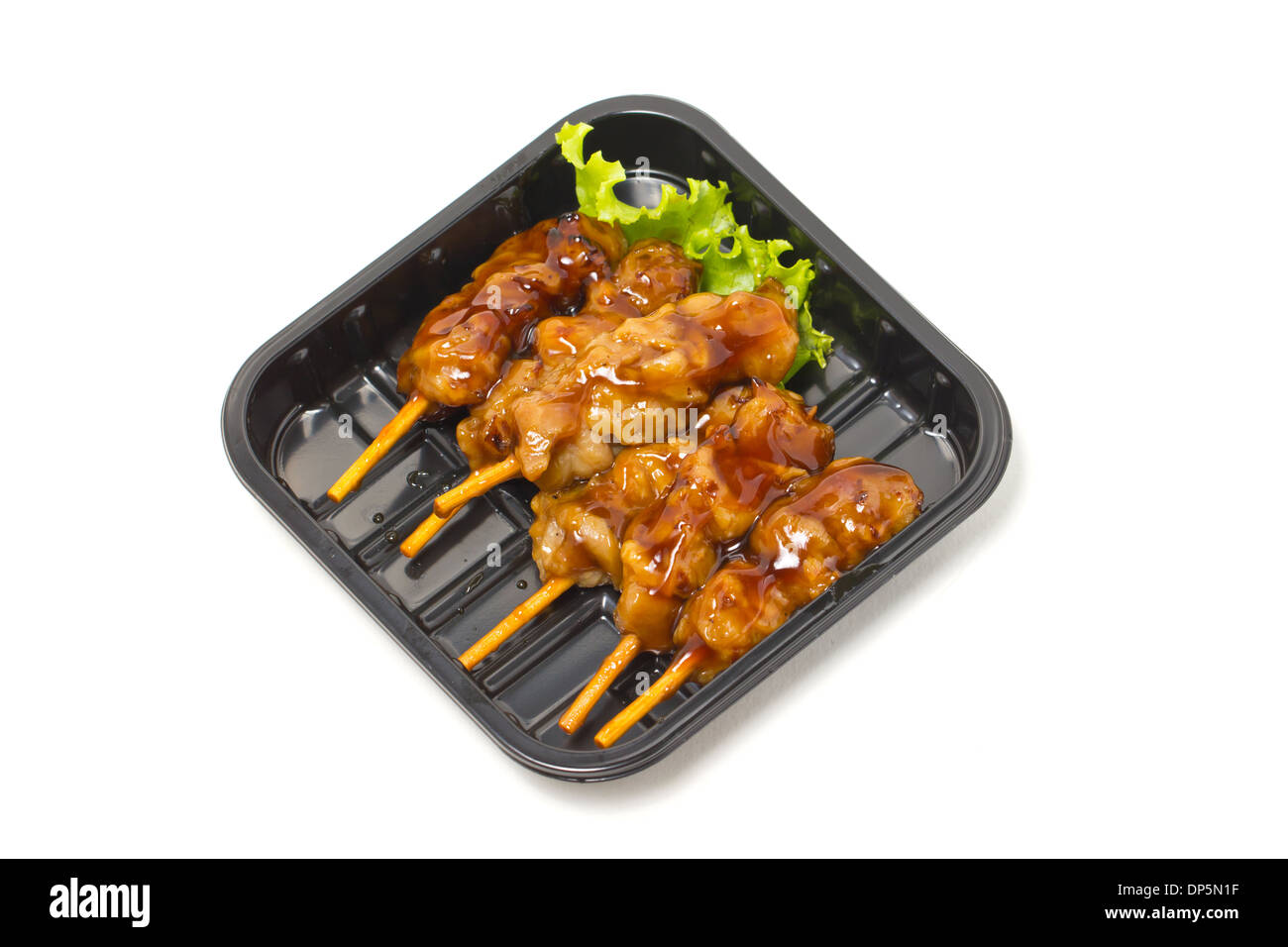 Pollo teriyaki spiedini con in tray nero isolato su bianco. Foto Stock