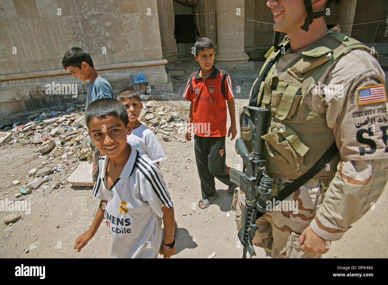 Ott 06 2006, Baghdad, Iraq; ragazzi iracheno camminare al fianco di Airman Prima Classe Brad Birkbeck di Baghdad IZ della polizia sui motivi di Saddam Hussein in ex teatro a Baghdad. Diverse famiglie irachene, spostato dopo il 2003 invasione, cercato rifugio nei resti di Saddam Hussein teatro personali, costruito per intrattenere l'ex presidente iracheno durante la sua regola. Le famiglie di paura Foto Stock