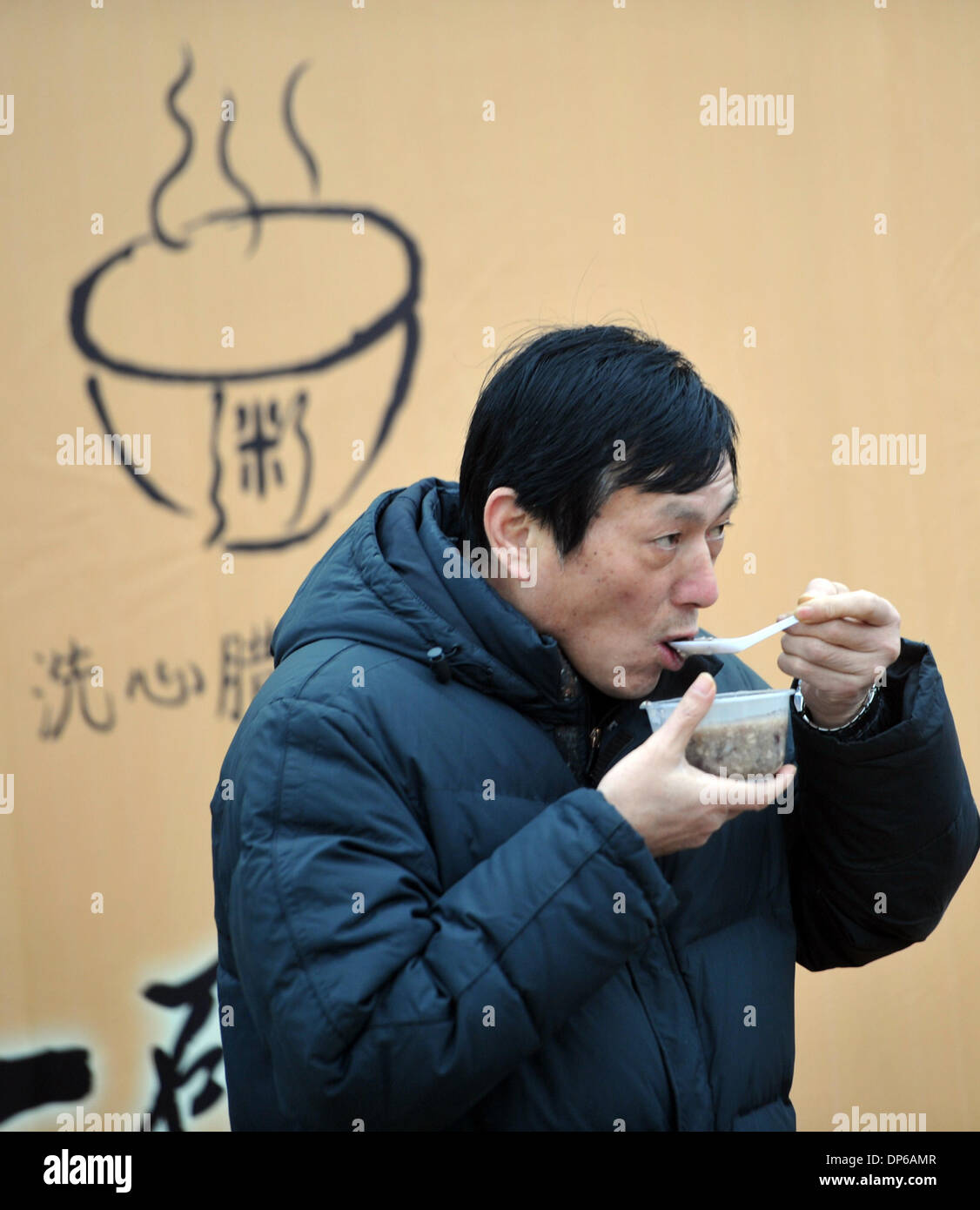 Changsha, provincia cinese di Hunan. 8 Gen, 2014. Un uomo mangia porridge gratuita presso il Tempio Xixin in Changsha, capitale della centrale provincia cinese di Hunan, 8 gennaio, 2014. Cinesi hanno la tradizione di mangiare il porridge sul Laba Festival, che è l'ottavo giorno del dodicesimo mese lunare e cadde il 8 gennaio di quest'anno. Molti templi e le organizzazioni hanno la tradizione di porridge di offerta al pubblico. Credito: Li Ga/Xinhua/Alamy Live News Foto Stock