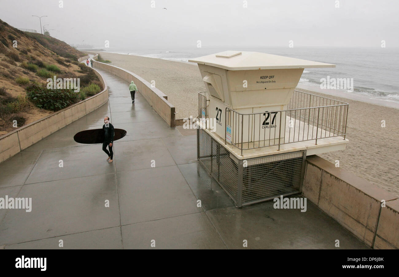 Oct 16, 2006; Carlsbad, CA, Stati Uniti d'America; Drizzly tempo grigio copre la costa come Carlsbad surfer KEITH SCHILLER passeggiate attraverso il Carlsbad Sea Wall dopo l'uscita dell'acqua e il surf onde piccole. Credito: Foto di Charlie Neuman/SDU-T/ZUMA premere. (©) Copyright 2006 by SDU-T Foto Stock