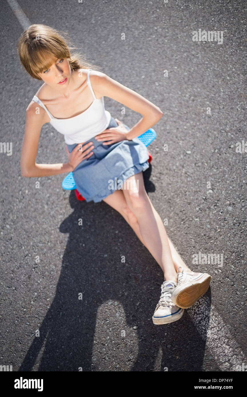 Moda giovane donna seduta sul suo skateboard Foto Stock