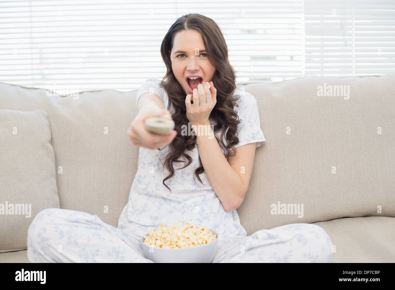 Pretty Woman in pigiama avente il popcorn durante la visione di un film di paura Foto Stock