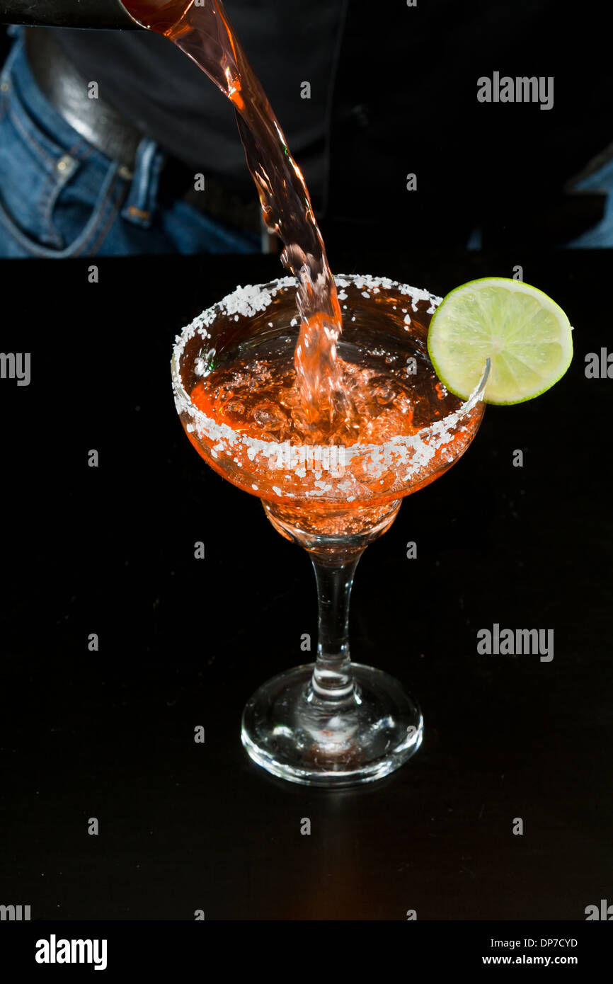 Azione girato di un barman versando un rosso margarita Foto Stock