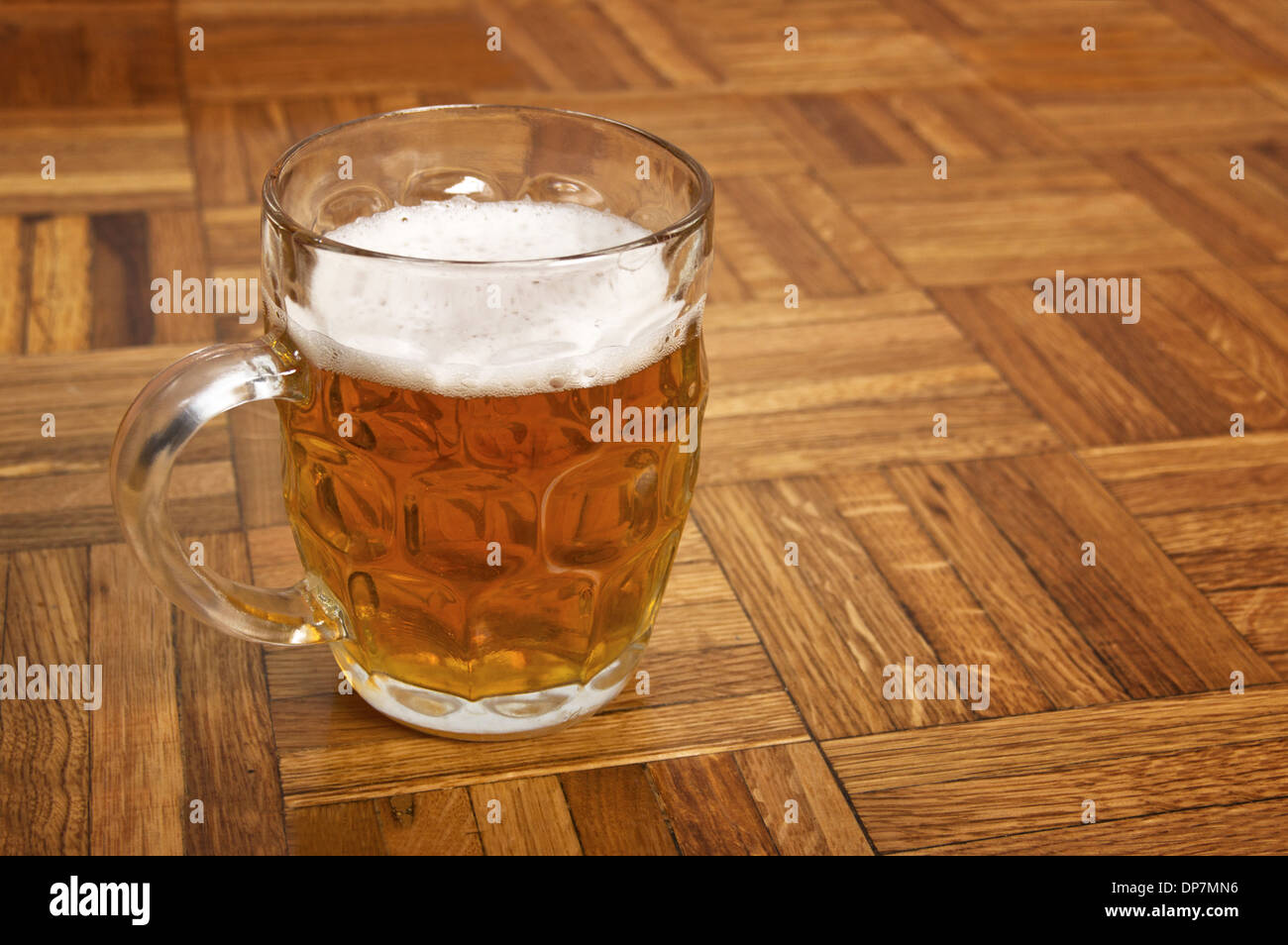 Boccale di birra fresca con tappo di gomma espansa su sfondo di legno. Foto Stock