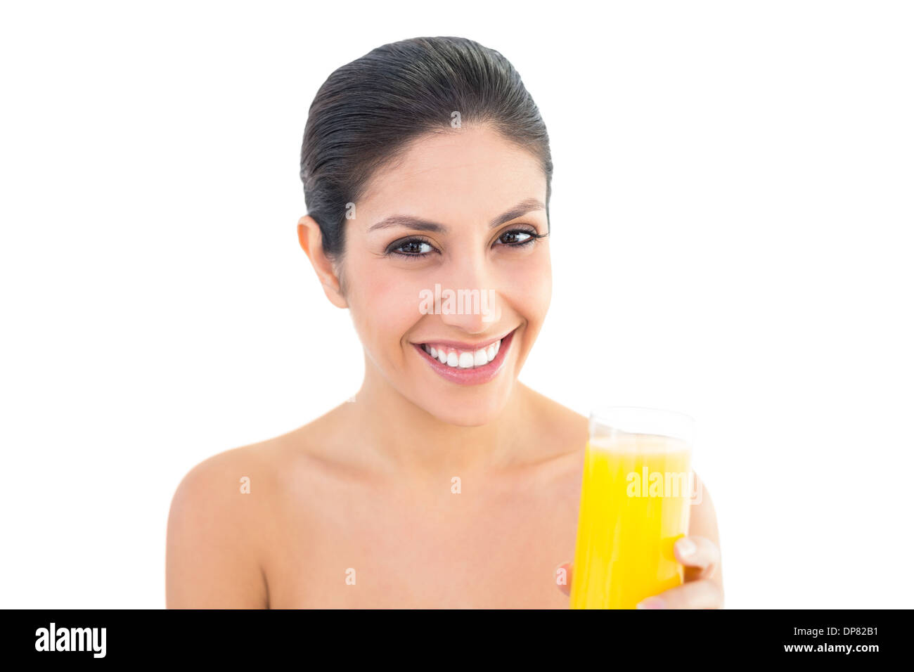 Bruna sorridente in telecamera tenendo un bicchiere di succo di arancia Foto Stock