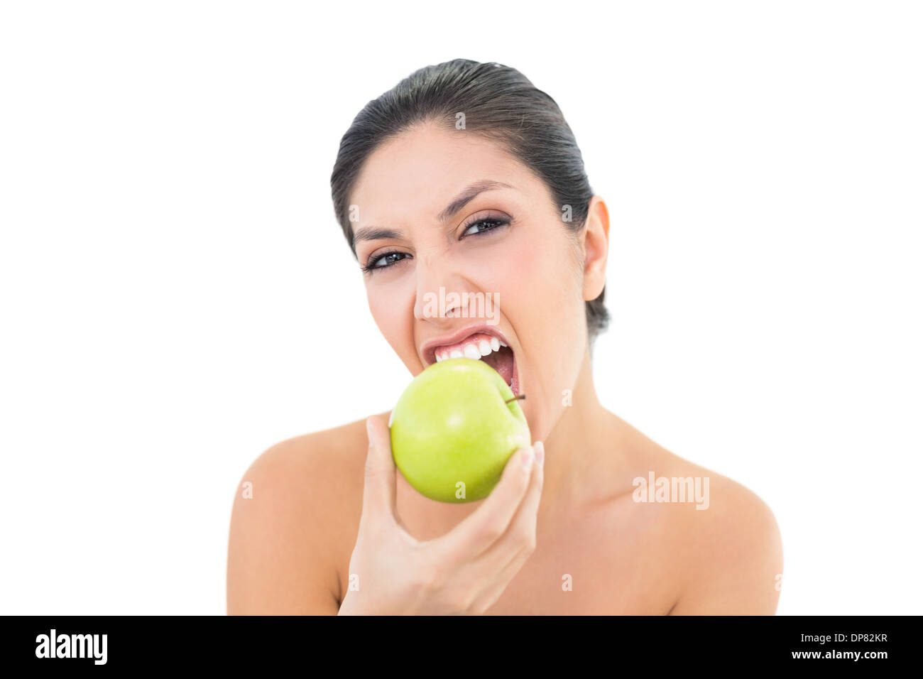 Happy brunette mangiare una mela verde e guardando la fotocamera Foto Stock