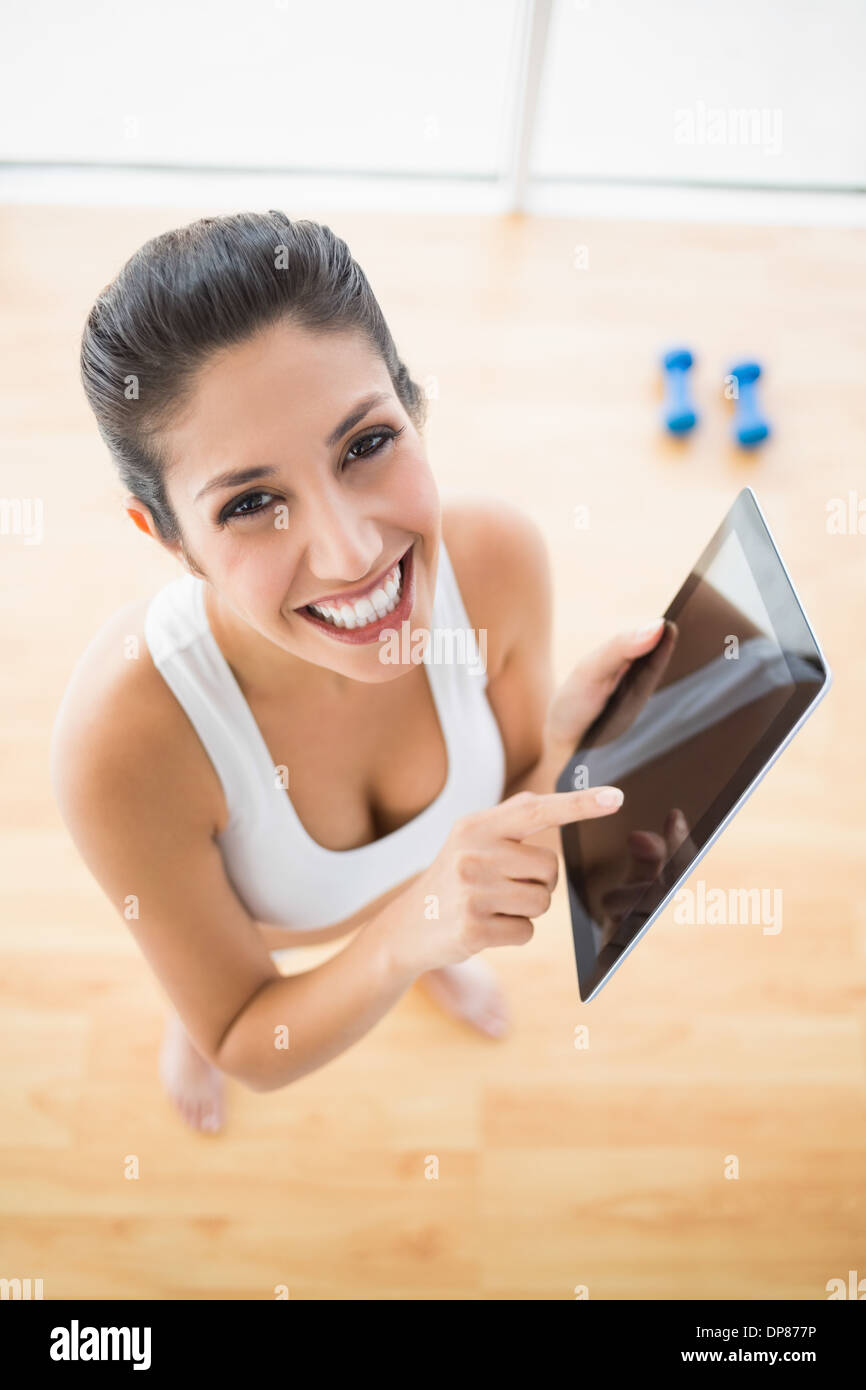 Montare donna utilizzando tablet prendendo una pausa dall'allenamento sorridente in telecamera Foto Stock