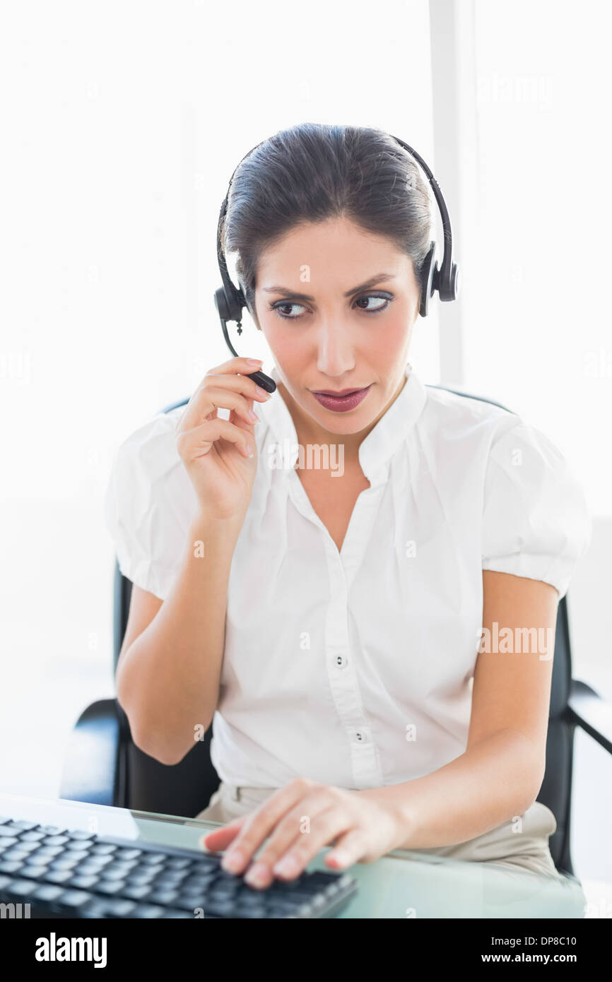 Gravi agenti del call center a lavorare alla sua scrivania su una chiamata Foto Stock