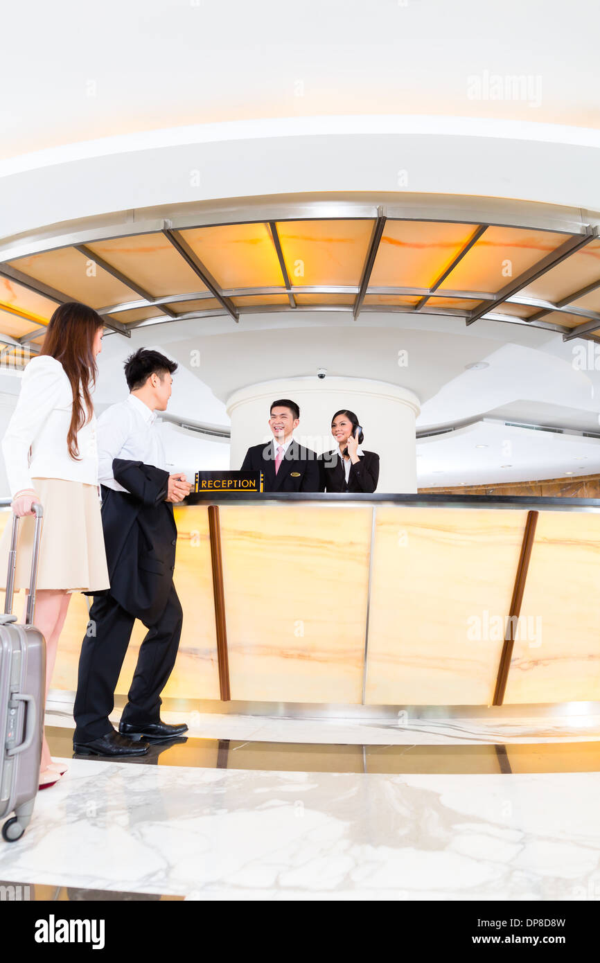 Cinese asiatica donna e uomo che arrivano al banco della reception o la  reception di Hotel di lusso in business vestiti con trolley Foto stock -  Alamy