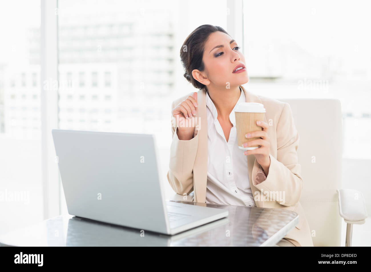 Pensando imprenditrice di bere il caffè mentre si lavora sul computer portatile Foto Stock