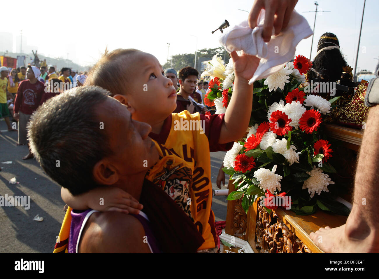 Manila, Filippine . 9 Gen, 2014. Un giovane bambino ottiene una salviettina da una replica del Nazareno nero a Manila nelle Filippine il 9 gennaio 2014. Migliaia di cattolici filippini gregge ogni anno a Manila per ottenere un assaggio della miracolosa figura. Foto di Mark Cristino Credito: Mark Fredesjed Cristino/Alamy Live News Foto Stock