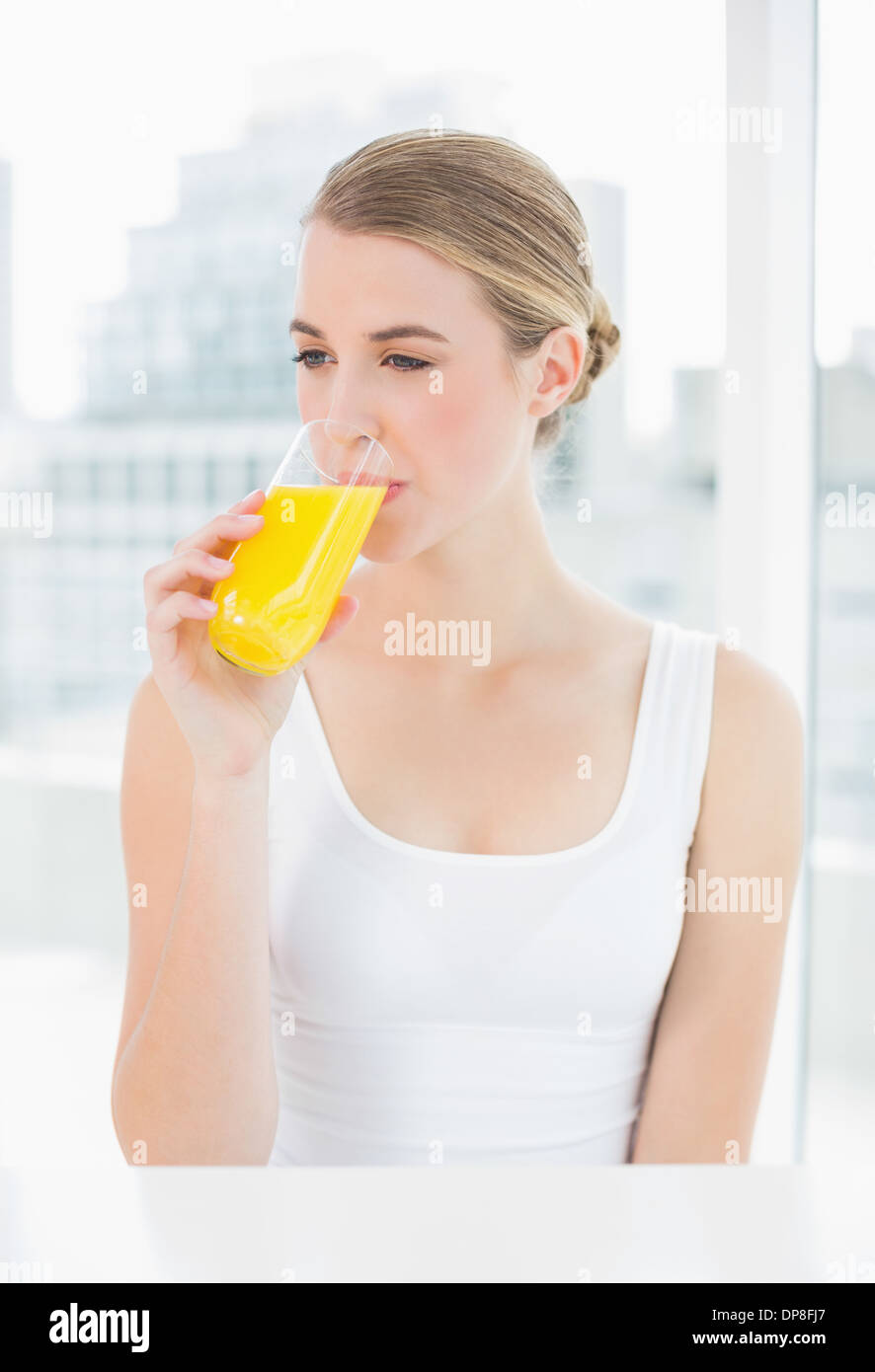 Carino donna bionda di bere succo di arancia Foto Stock