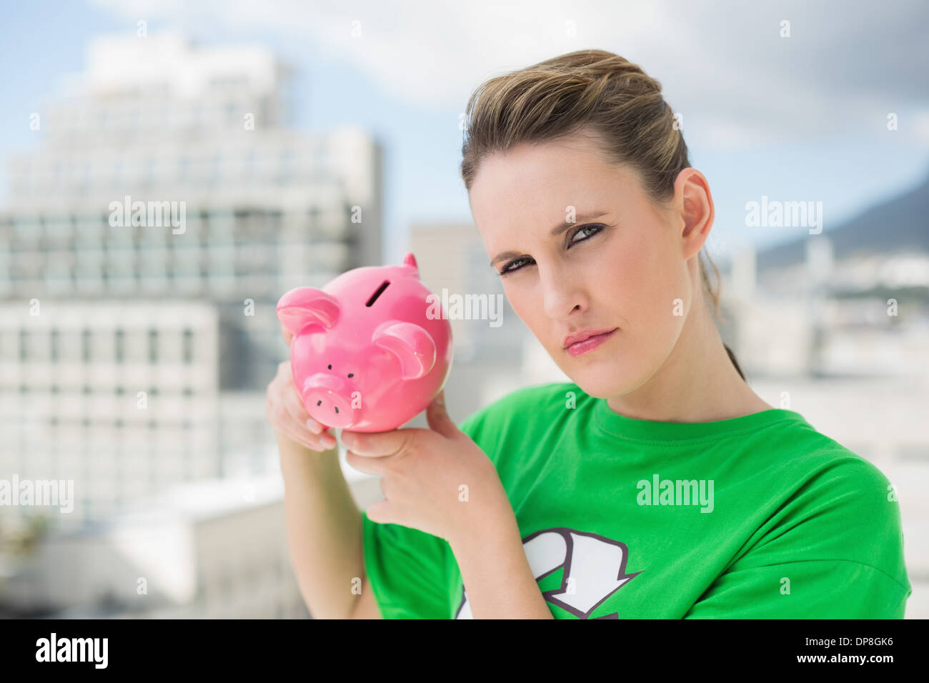Grave donna che indossa il riciclaggio verde tshirt holding salvadanaio Foto Stock