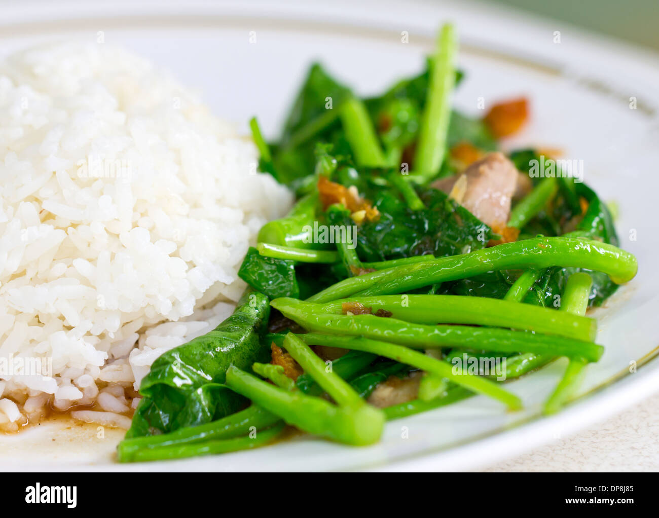 Broccoli cinesi o cavoli cinesi fritti con croccante maiale accanto al riso al vapore. Foto Stock