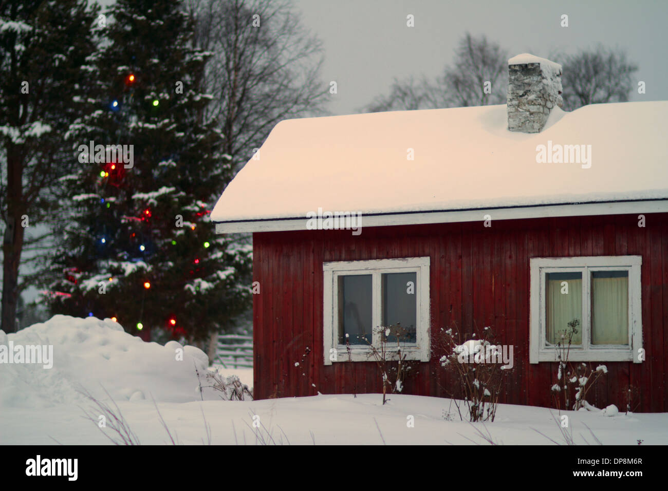 Casa in legno rosso con sensazione di Natale in inverno nordico con la neve Foto Stock