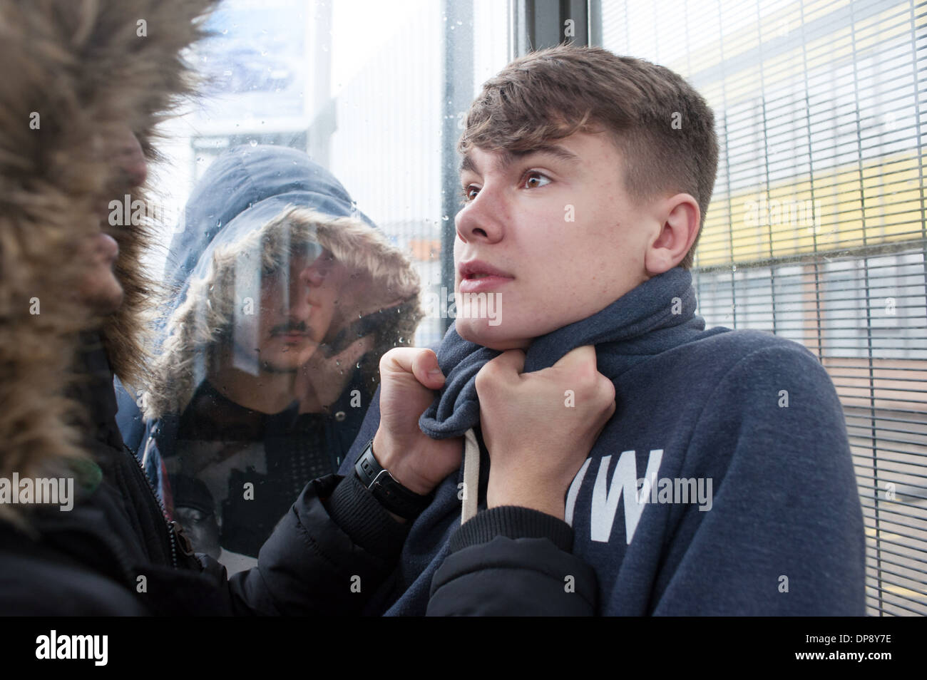 Un giovane uomo di essere vittima di bullismo a una fermata da un gruppo di ragazzi adolescenti. Foto Stock