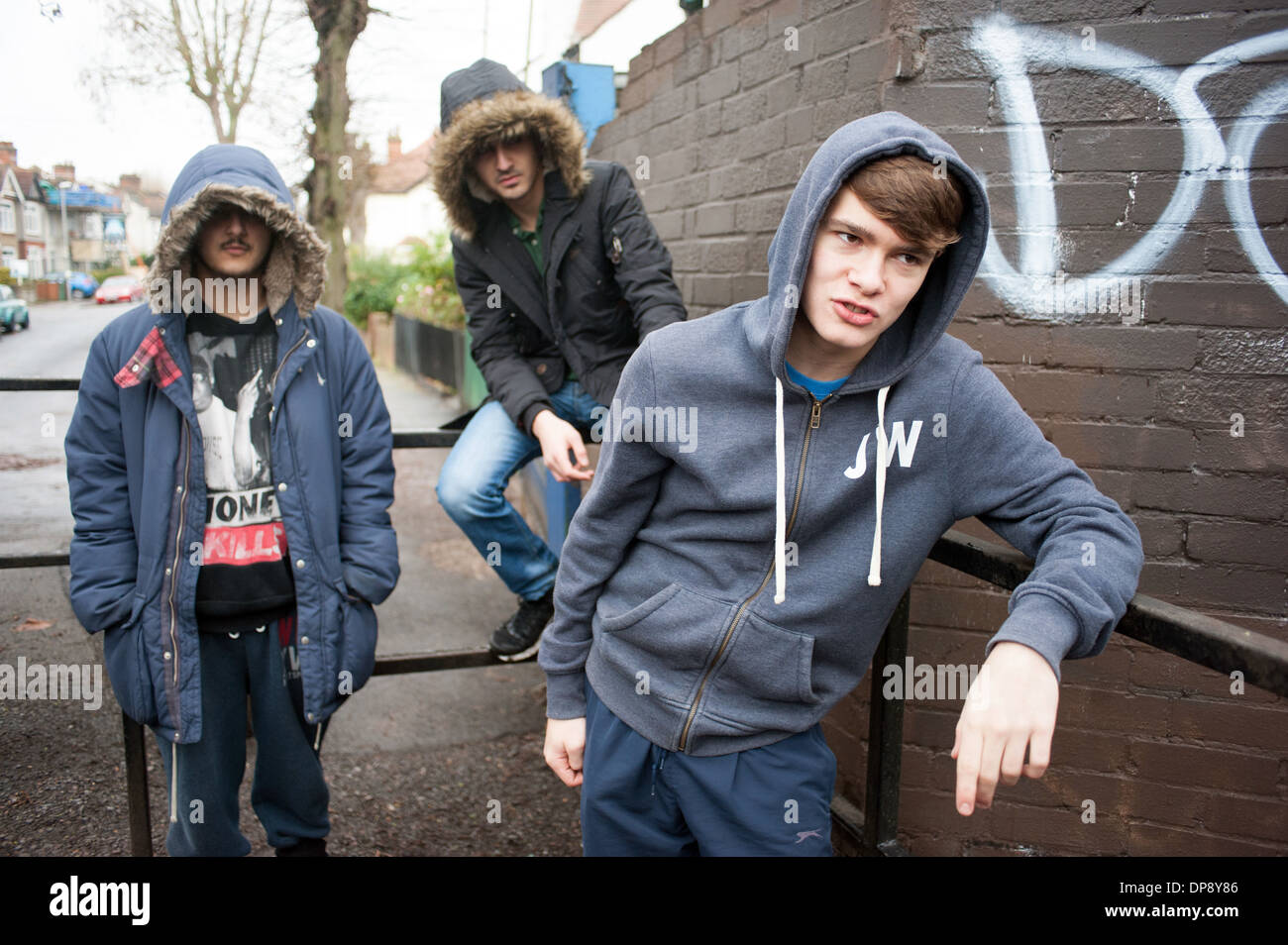 Un gruppo di ragazzi adolescenti in giro chiacchiere su un angolo di strada cercando intimidatorio e minaccioso. Foto Stock