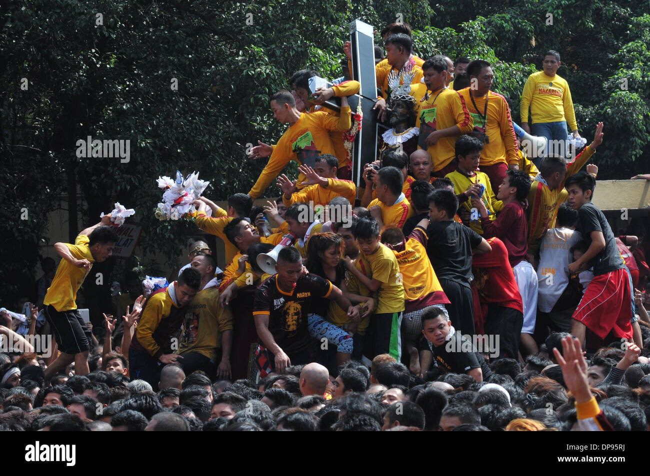 Manila, Filippine. Il 9 gennaio, 2014. MANILA, Filippine - Cattolici devoti filippino aiutano gli altri a salire il carrello dell'immagine come essi prendono parte all'annuale ''Traslacion'', termine spagnolo per il movimento o passaggio, durante la festa del Nazareno nero a Manila . Il Nazareno nero è un vecchio di secoli l immagine di Gesù Cristo che porta la croce e che è ampiamente creduto di compiere miracoli. ws Credito: ZUMA Press, Inc./Alamy Live News Foto Stock