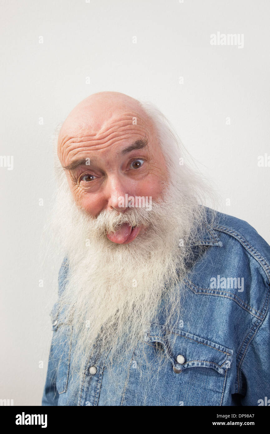 Ritratto di uomo anziano spuntavano lingua su sfondo grigio Foto Stock