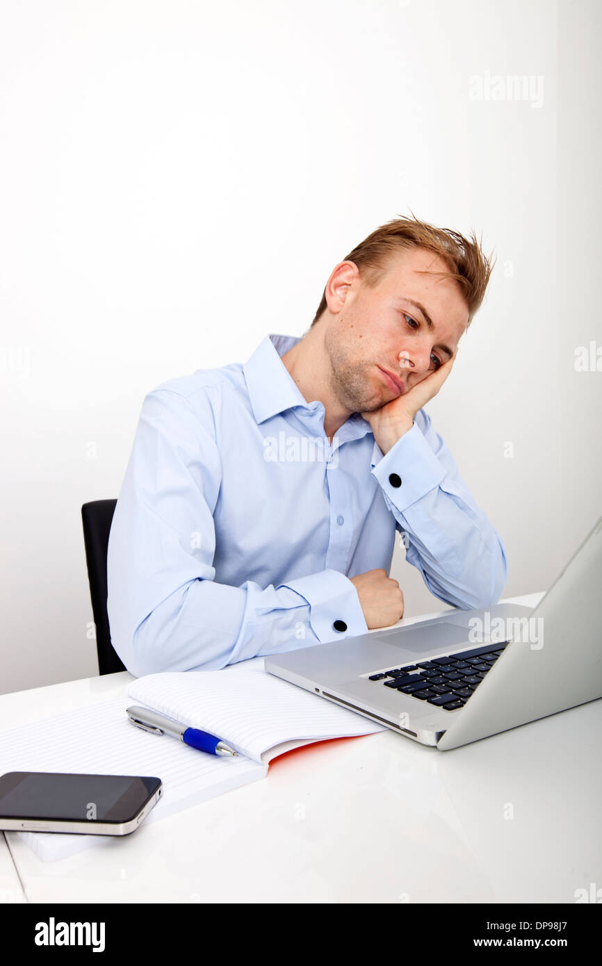 Stanco imprenditore con laptop sulla scrivania in ufficio Foto Stock