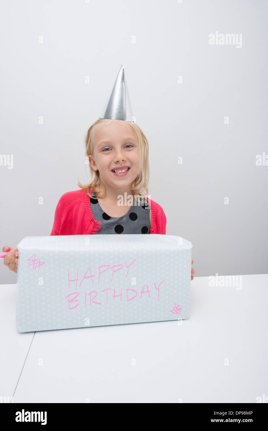 Ritratto di una ragazza con il regalo di compleanno a tavola in casa Foto Stock