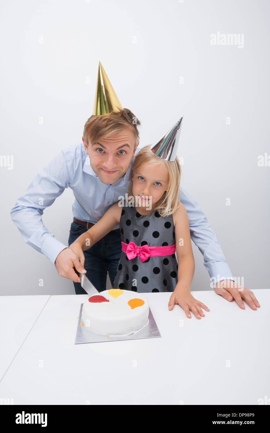 Ritratto di padre e figlia di taglio la torta di compleanno a tavola Foto Stock