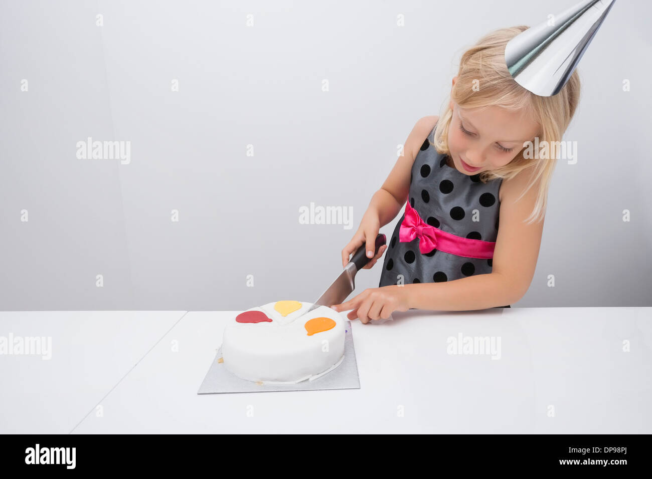 Ragazza il taglio di torta di compleanno a tavola in casa Foto Stock