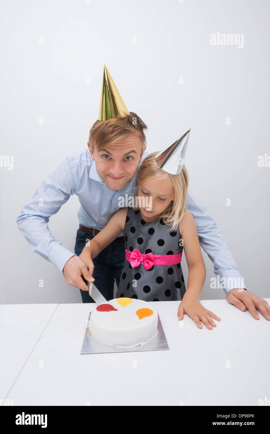 Ritratto di Padre sorridente il taglio di torta di compleanno con la figlia a tavola Foto Stock